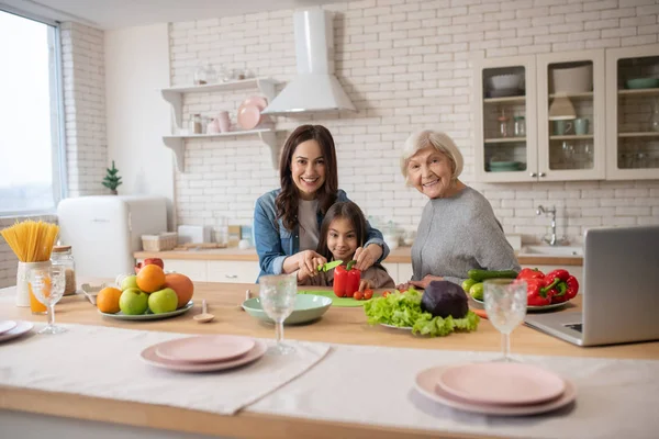 Nevető nagymama és lánya együtt a konyhaasztal mellett. — Stock Fotó