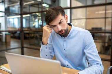 Bearded man in a blue shirt looking involved and serious