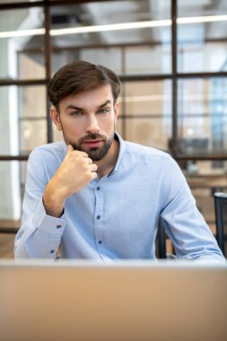 Bearded man in a blue shirt thinking about new project