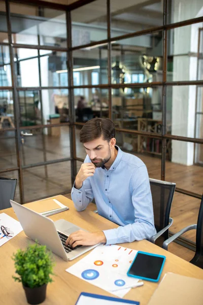 Bearded man in a blue shirt sitting in the office — Stock Fotó