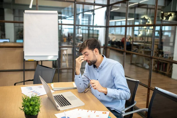 Bearded man in a blue shirt feeling tired after work — Stock Photo, Image