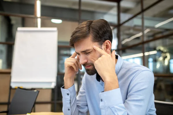 Bearded man in a blue shirt suffering from a strong headache — Stock Photo, Image