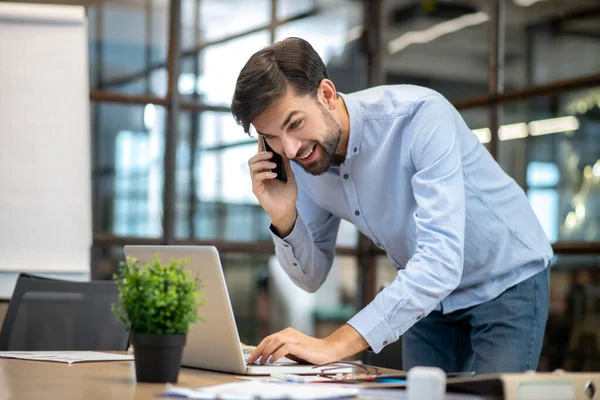 Jonge man met een baard in een blauw shirt aan de telefoon aan het praten en zijn post aan het checken — Stockfoto