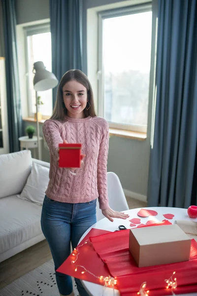 Donkerharig meisje in een roze shirt en jeans met een rode geschenkdoos — Stockfoto