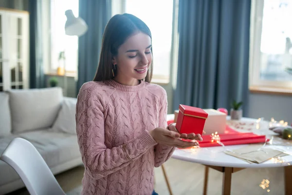 Gadis berambut gelap dalam kemeja merah muda memegang kotak hadiah — Stok Foto