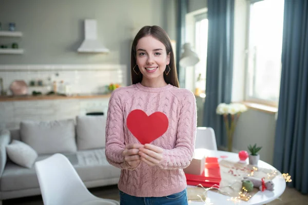 Красивая молодая девушка в розовом держит бумажное сердце — стоковое фото