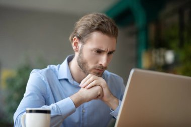 Laptop ekranına bakan odaklanmış genç bir adam.