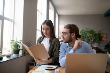 Dosyası olan bir kız ve ofiste dizüstü bilgisayarı olan bir adam..