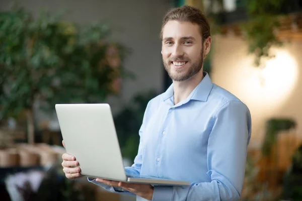 Ung leende man med en bärbar dator i händerna. — Stockfoto