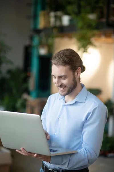 Молодий чоловік у світло-блакитній сорочці з ноутбуком в руках . — стокове фото