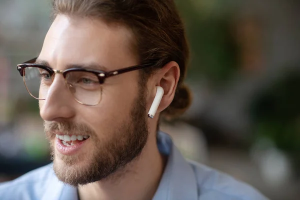 Happy face of man in glasses and in one wireless earpiece.