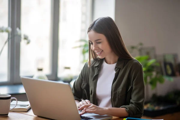 Ung flicka som arbetar på en bärbar dator på ett kontor. — Stockfoto