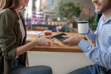 Erkek ve kadın akıllı telefonu birlikte kullanırken uzatıyorlar.