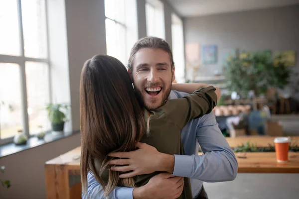 Sorridente uomo barbuto abbracciando il suo amico femminile — Foto Stock