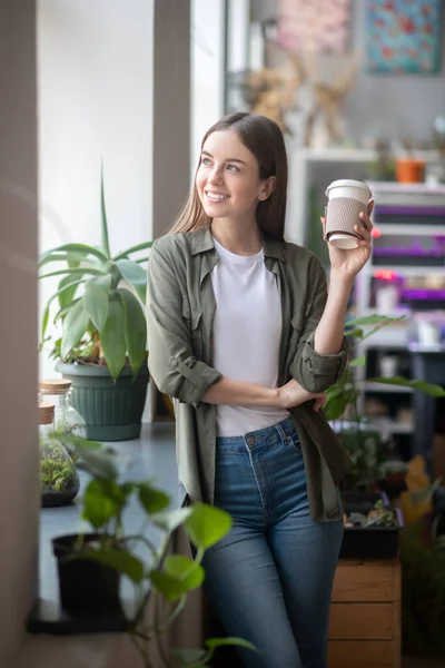 Mujer sonriente engreyendo mientras toma un café — Foto de Stock