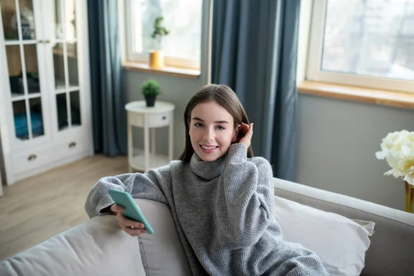 Menina de cabelos escuros em uma camisola cinza olhando bonito — Fotografia de Stock