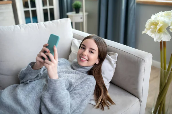 Chica joven en un suéter gris descansando en casa — Foto de Stock