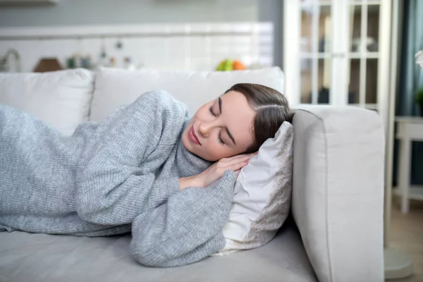 Chica joven en un suéter gris durmiendo tranquilamente — Foto de Stock