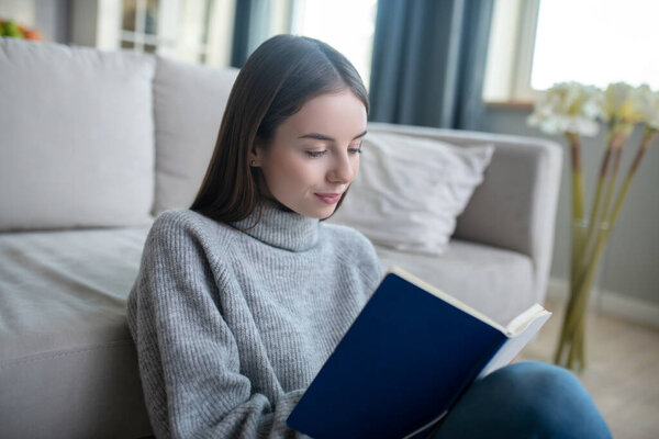 Young girl in a grey sweater making notes in her diary