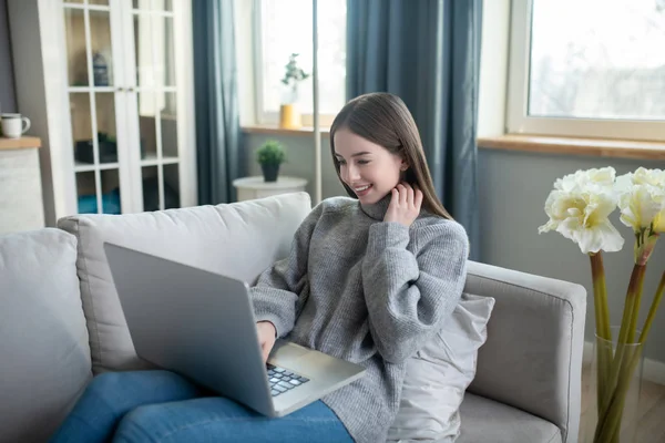 Chica joven en un suéter gris pasar tiempo en internet — Foto de Stock