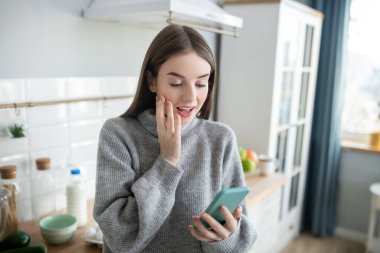 Dark-haired girl in a grey sweater looking surprised