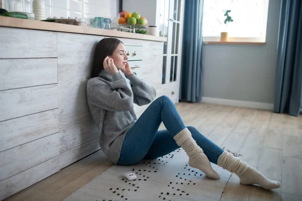 Dark-haired girl in a grey sweater wearing wireless headphones — Stock Photo, Image