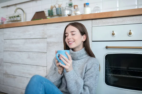 Fille aux cheveux foncés dans un pull gris profitant du café du matin — Photo