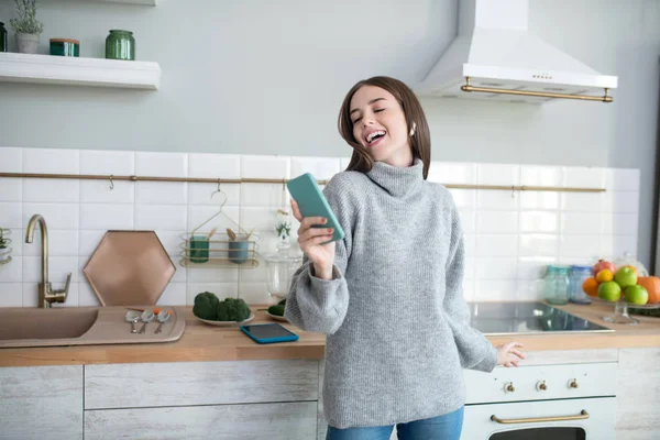 Dark-haired girl in a grey sweater enjoying and making selfie — Stok fotoğraf