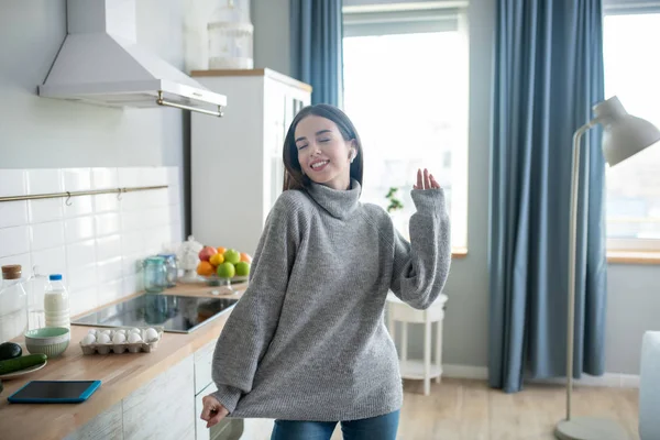 Dark-haired girl in a grey sweater feeling joyful — Stockfoto