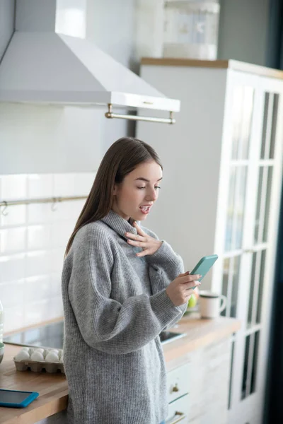 Dark-haired girl in a grey sweater looking stressed — Stok fotoğraf