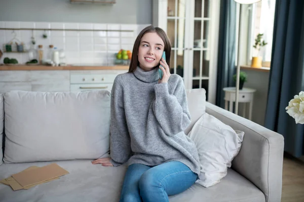 Dark-haired girl in a grey sweater having a call — Stok fotoğraf