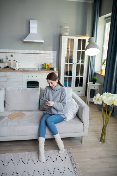 Dunkelhaariges Mädchen in grauem Pullover sitzt in ihrem Zimmer — Stockfoto