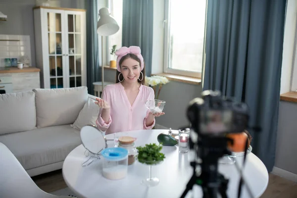 Sonriente chica bonita en una diadema rosa haciendo un video sobre el cuidado de la belleza — Foto de Stock