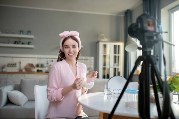 Νέο όμορφο κορίτσι σε ένα ροζ κεφαλόδεσμο κάνει ένα βίντεο — Φωτογραφία Αρχείου