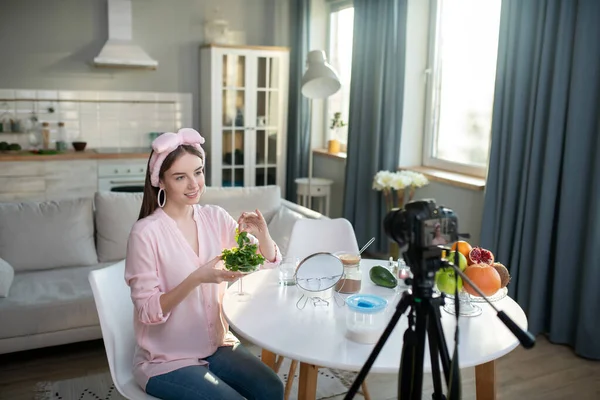 Joven chica bonita en una camisa rosa haciendo un video sobre el cuidado de la piel — Foto de Stock