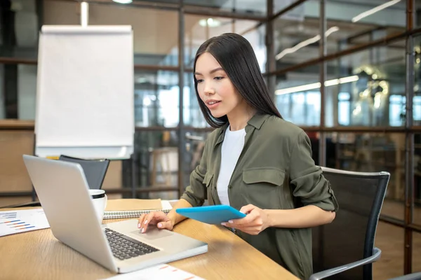 Long-haired brunette asian girl working on a laptop — Stockfoto