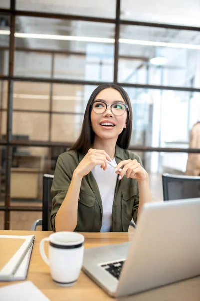 Langhåret brunette asiatisk pige arbejder på kontoret og føler sig glad - Stock-foto