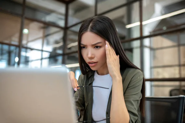 Long-haired brunette asian girl working in the office and suffering a headache — Stockfoto