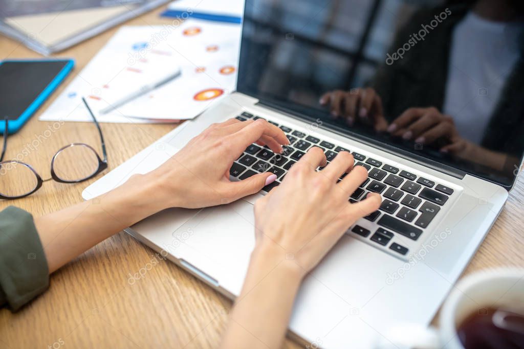 Close up picture of womans hands typing on laptop