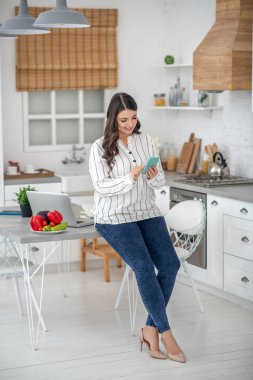 Long-haired woman in a striped blouse reading a message