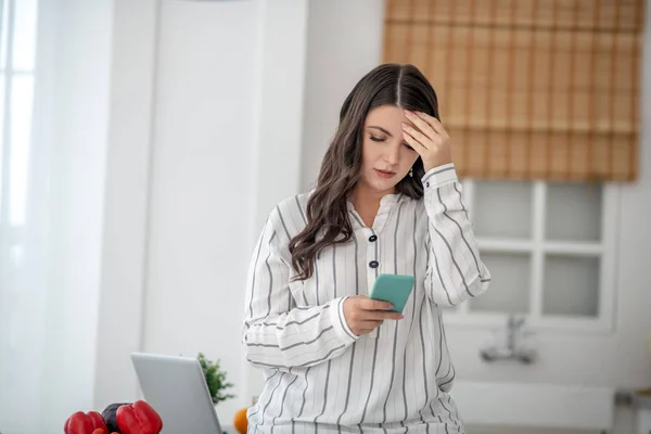 Long-haired woman in a striped blouse looking stressed — Stockfoto