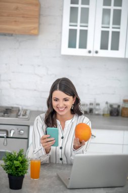 Long-haired woman in a striped blouse holding an orange