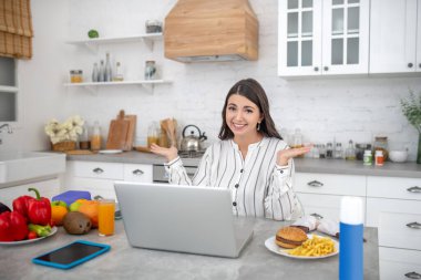 Dark-haired woman in a striped blouse thinking about food