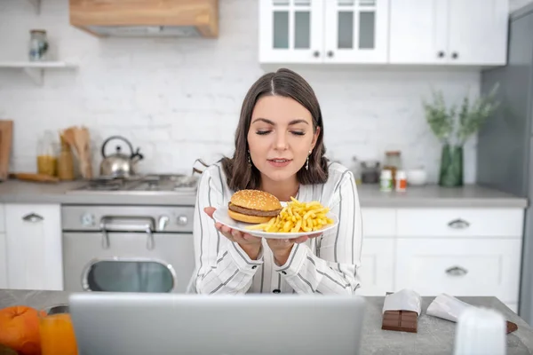 Mujer morena en blusa rayada disfrutando de comida malsana — Foto de Stock