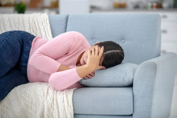 Jovem de corpo inteiro com uma camisa rosa deitada em um sofá — Fotografia de Stock
