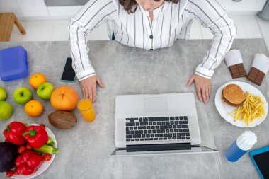 Dark-haired woman in a striped blouse sittimg at the table