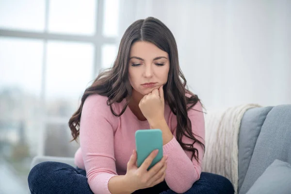 Full-figured young woman in a pink shirt holding a smartphone — Stockfoto