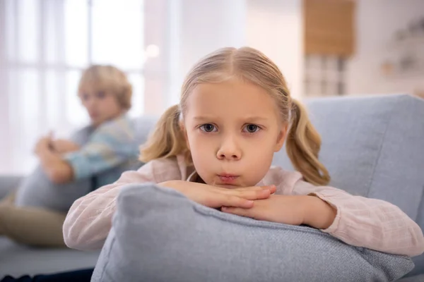 Blond cute girl with a pillow in her hands frowning — Stock Photo, Image