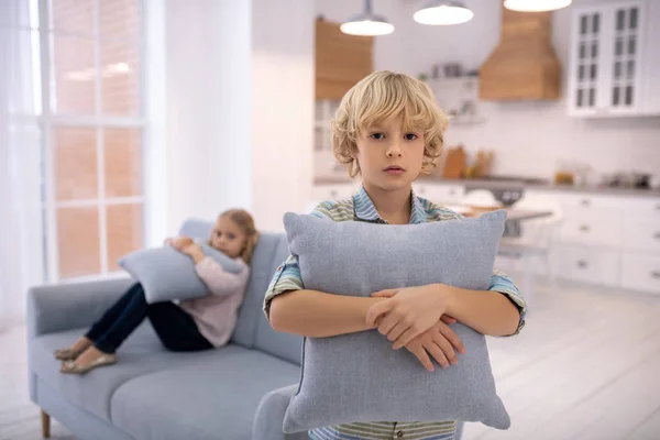 Blond cute boy with a pillow in his hands feeling moody — 스톡 사진