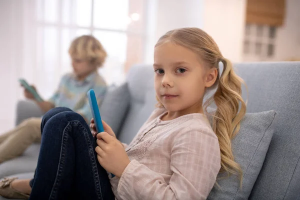 Dziewczyna trzyma tablet, chłopiec siedzi obok niej — Zdjęcie stockowe